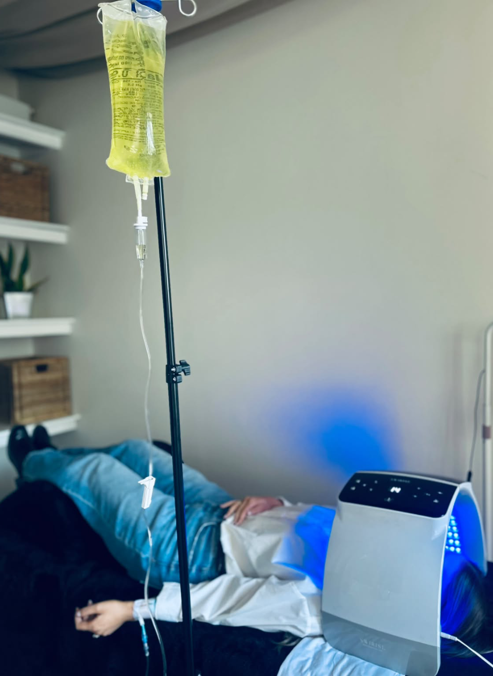 Client receiving IV therapy alongside LED light therapy